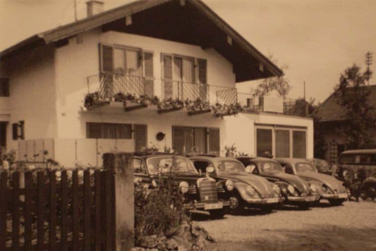 Wohnhaus mit mehreren Oldtimern vor dem Gebäude, frühe Unternehmensjahre von Diebald Lackierung.