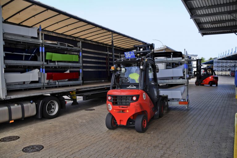 Gabelstapler verladen lackierte Fahrzeugteile in einen LKW zur Auslieferung bei Diebald Lackierung.